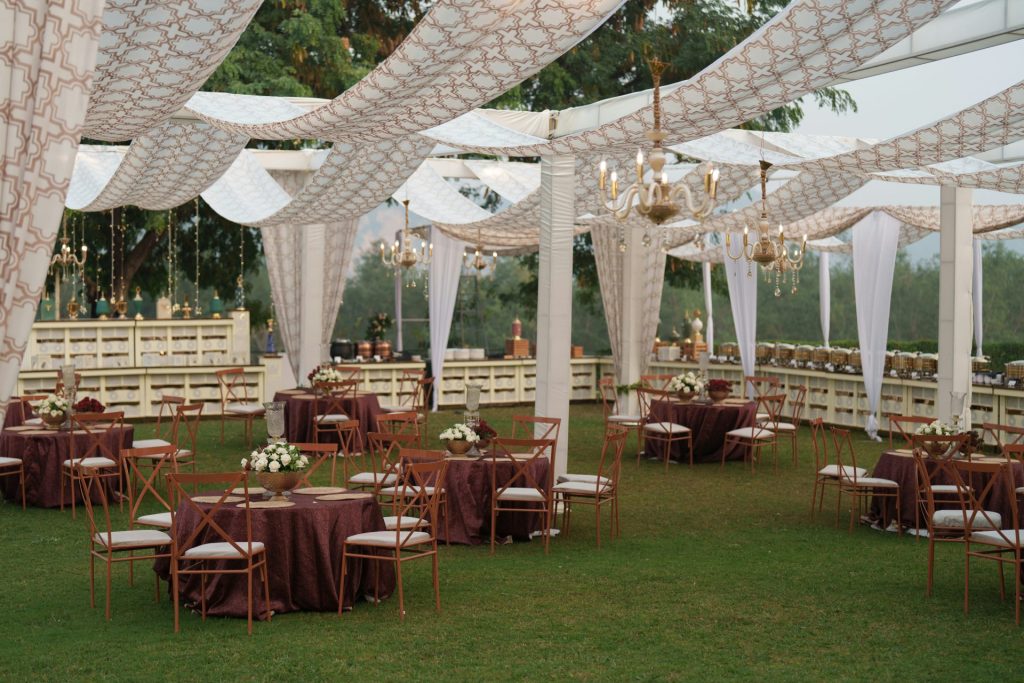 Elegant outdoor wedding reception with draped canopy and tables.